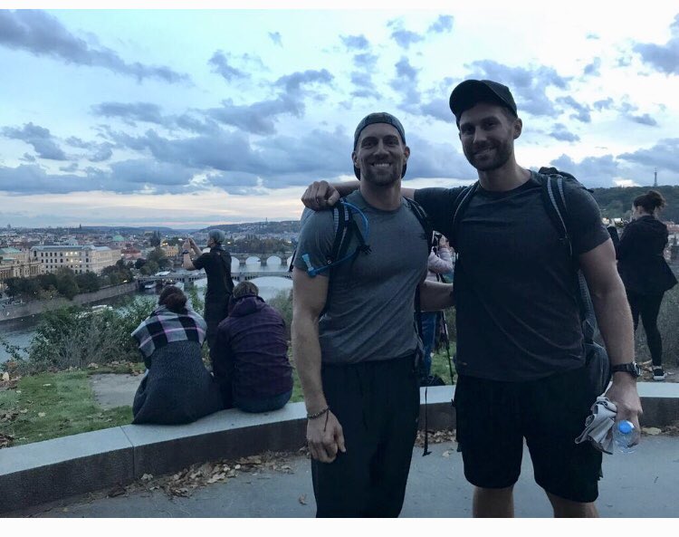 chrisjmarchant's tweet photo. I just got this picture yesterday; it was taken in Prague right after Trevor and I were eliminated in #theamazingrace, but we were still all smiles. The gorgeous scenery made for a great sendoff. #teamwellstrung https://t.co/yhTWHzjMJl