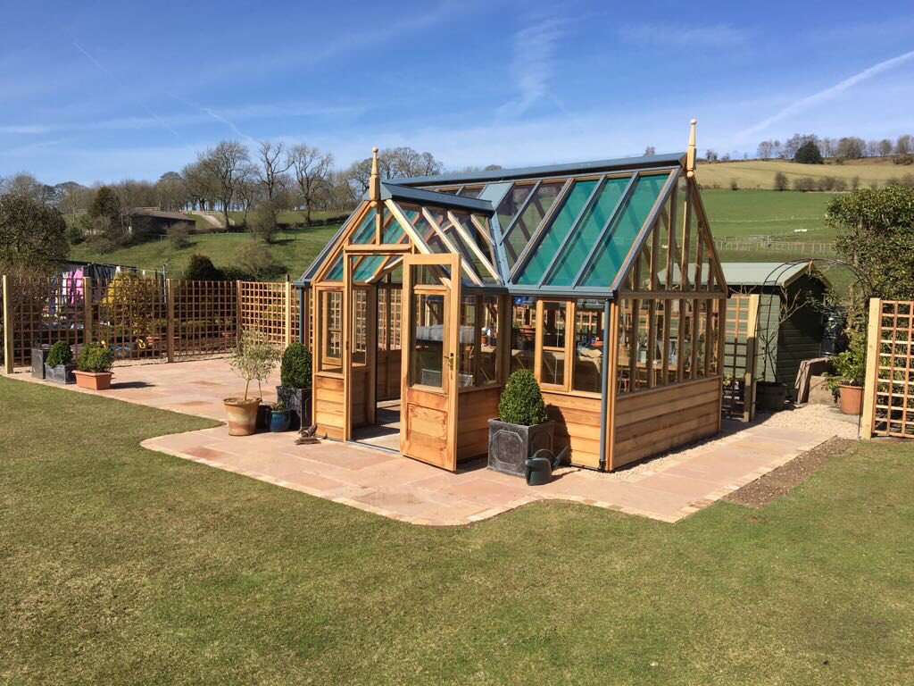 Greenhousebase's tweet photo. A beautiful greenhouse with a beautiful view! A perfect day to finish and photograph this project we designed with a @GabrielAsh11 Portico at the center of the project surrounded by paving, cedar wood trellis panels and custom built garden arches @allweldltd #GabrielAsh https://t.co/7pCDVOFwG8