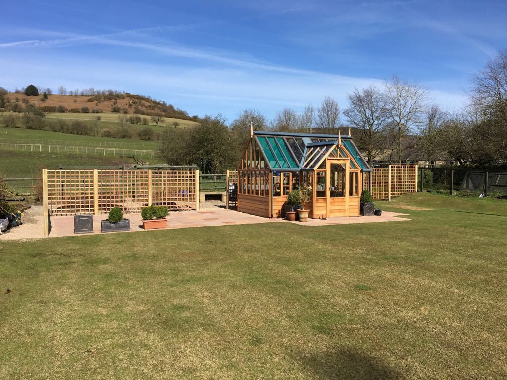 Greenhousebase's tweet photo. A beautiful greenhouse with a beautiful view! A perfect day to finish and photograph this project we designed with a @GabrielAsh11 Portico at the center of the project surrounded by paving, cedar wood trellis panels and custom built garden arches @allweldltd #GabrielAsh https://t.co/7pCDVOFwG8