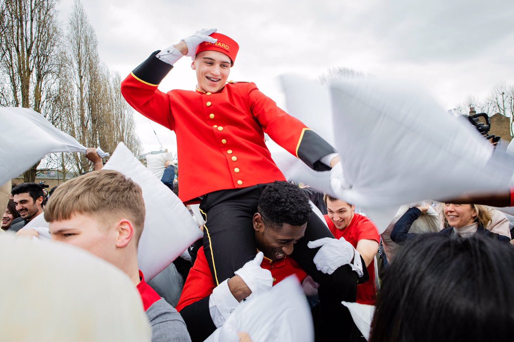 cunardline's tweet photo. Ever wondered about our pillow concierge? Our Bell Boys joined hundreds in London today for a mass pillow fight to celebrate #InternationalPillowFightDay https://t.co/yOadoVCsG3