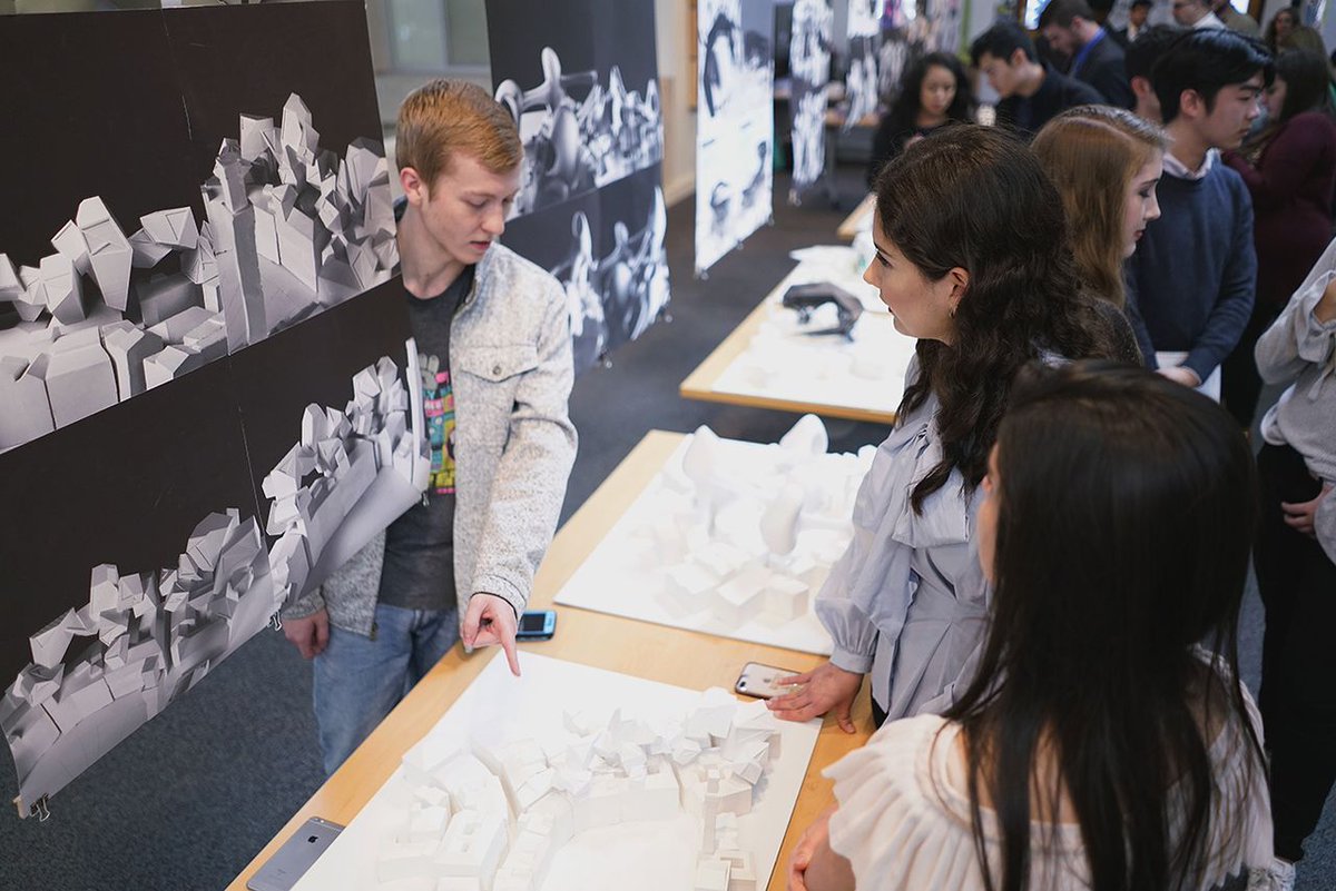 people pointing at a model and standing around designs