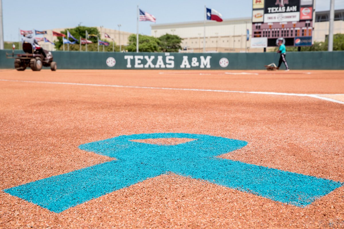 A teal ribbon painted on dirt on the field