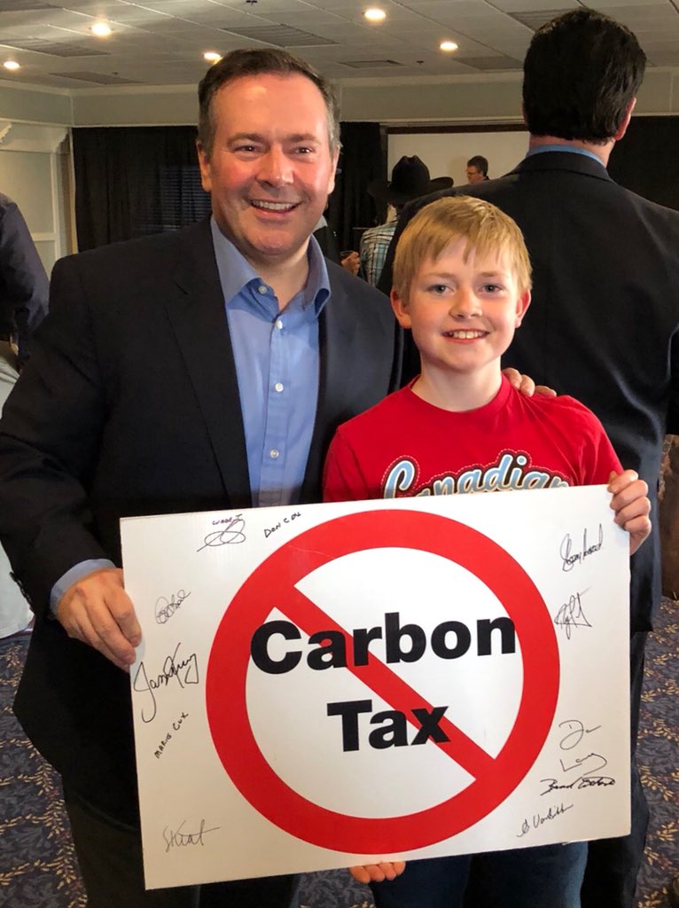 jkenney's tweet photo. Up in the amazing #Yukon territory talking about the need to fight for Canada’s resource industries. Can’t find anyone here who supports Liberal - NDP carbon taxes! Young Will here bought this 🚫carbon tax sign at a silent auction with his own money. https://t.co/vmpGfZjkHx