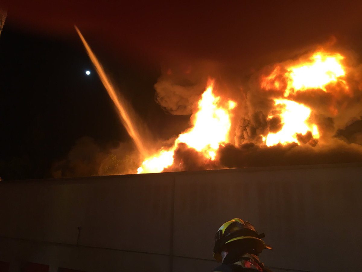 OCFireAuthority's tweet photo. Laguna Hills Structure Fire. 25000 Block of Costeau. 2 story self storage unit. Fire through the roof. 4 alarms. Partial wall and roof collapse. 90 firefighters onscene. Defensive fire attack. No injuries reported. https://t.co/jbNzmhi7rg