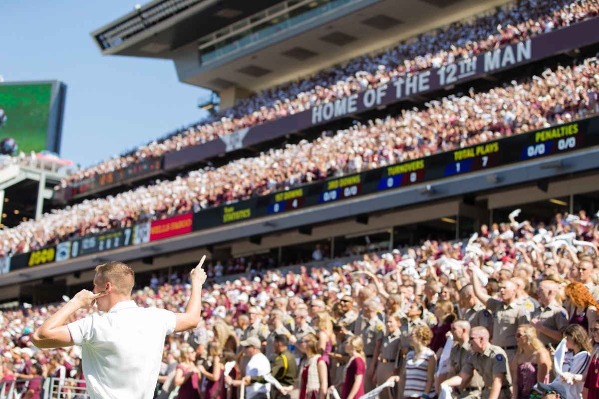 A yell leader standing in front of a fulls student section at Kyle field leading Aggies in a yell