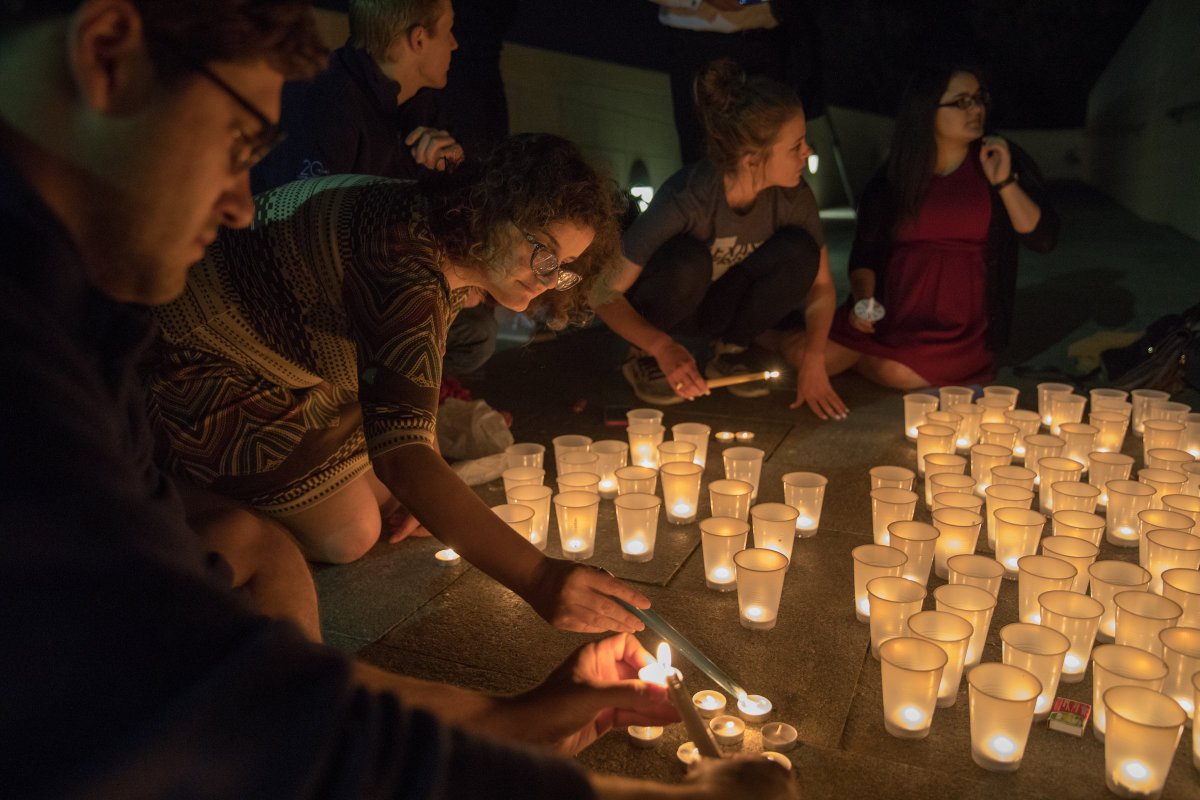 students lighting candles on the ground outside of the library