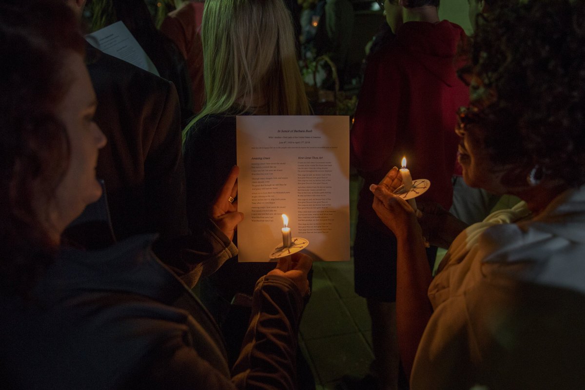 Students holding up candles to a program to read words to a hymn