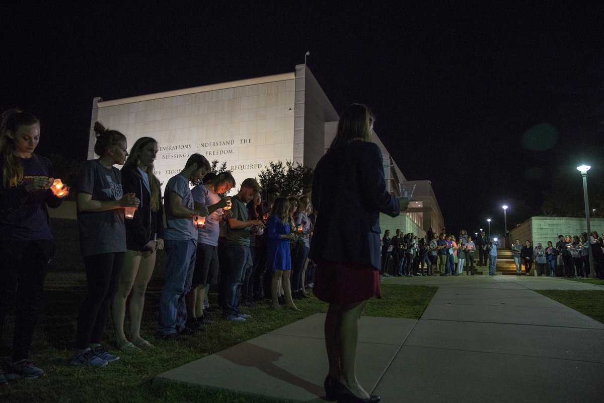 dozens of students standing with candles outside of the Bush School