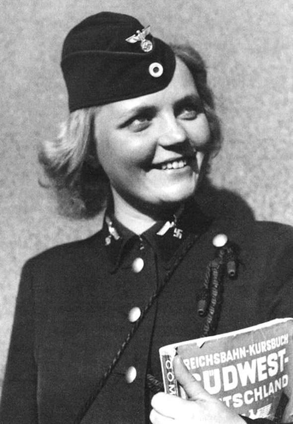 Glockengeist's tweet photo. A Reichsbahn employee. She is holding a railway guide to Southwest Germany. https://t.co/2zCbkT857c