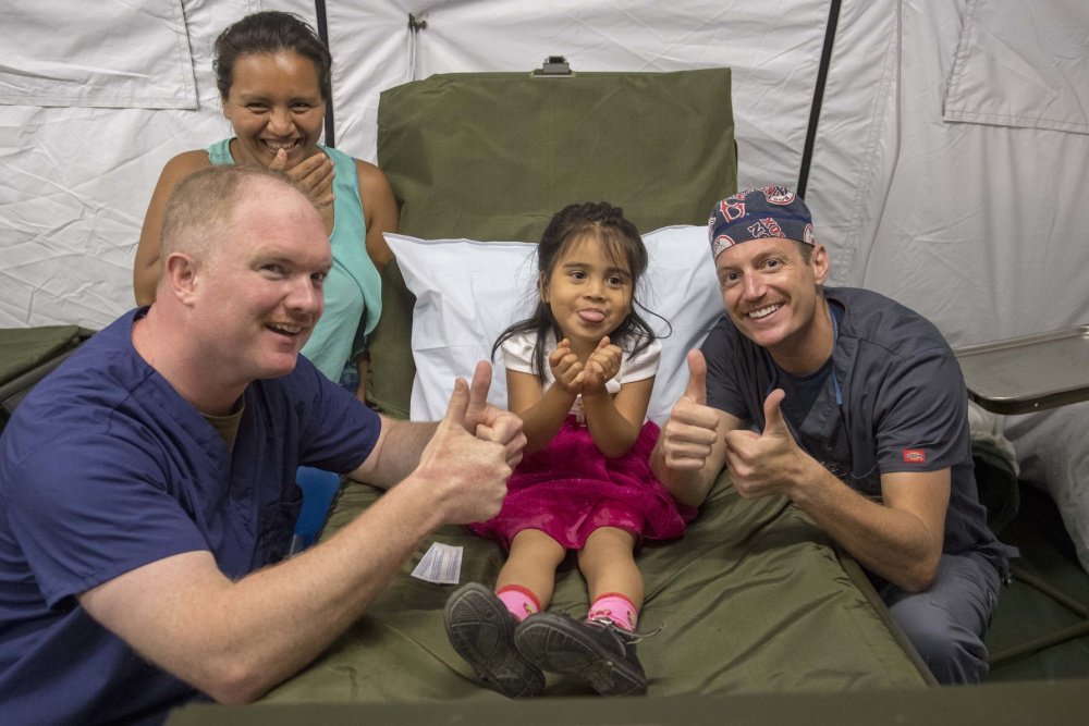 NavyMedicine's tweet photo. Lt. Cmdr. Conor Garry and Lt. Cmdr. Jason Souza give a thumbs up with a Guatemalan girl in Puerto Barrios during @usnavy_cp 2018 in this week's #NavyMedicine photo of the week. Keep up the good work! https://t.co/NJkxmtjA5x
