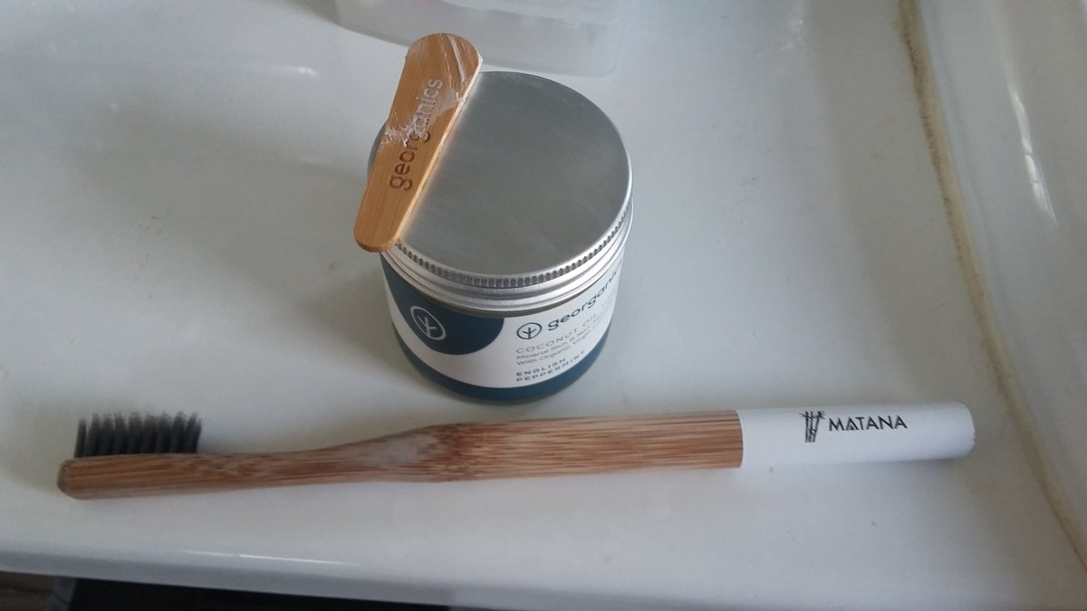 Small steps. Wooden toothbrush and a glass jar of toothpaste.