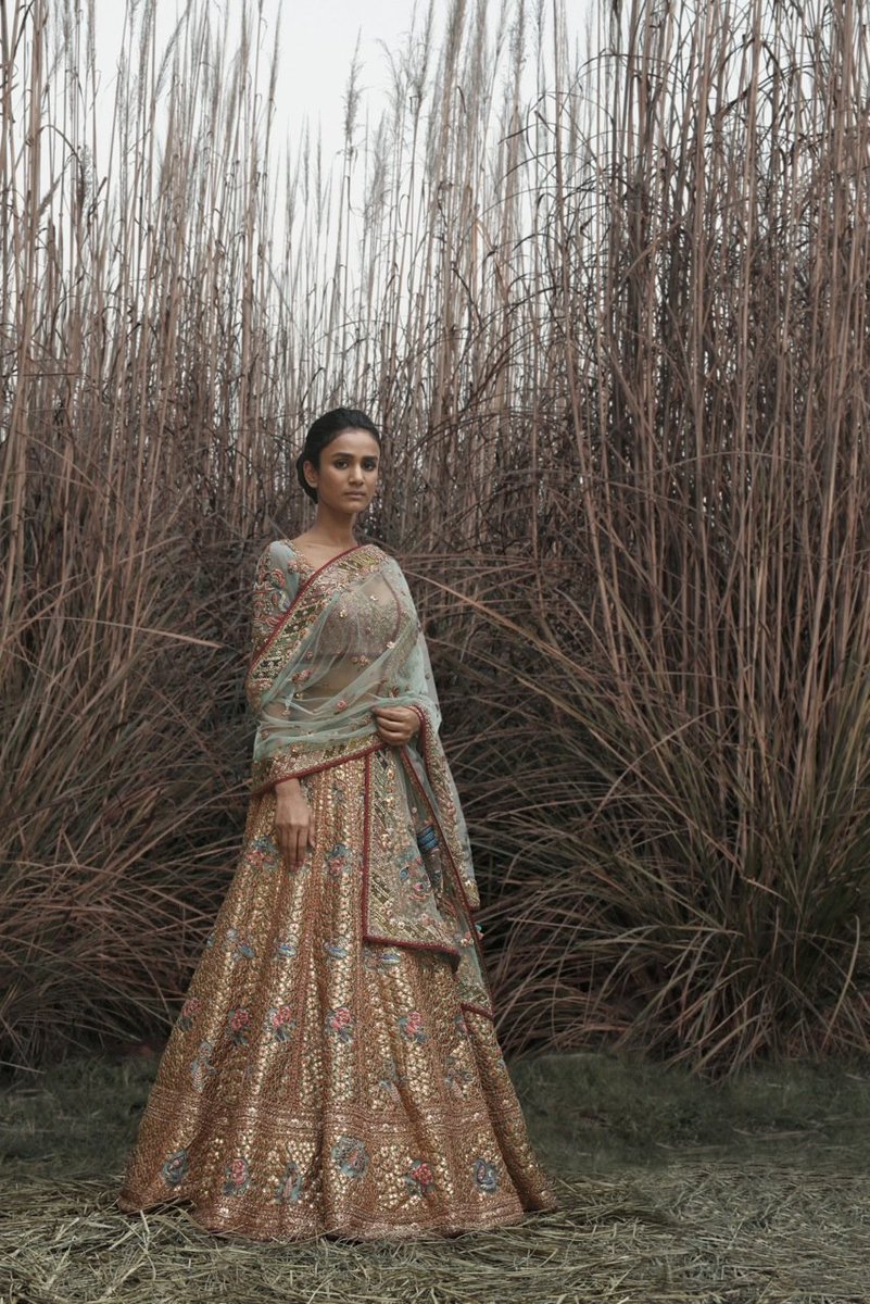 A pale tourmaline green tulle lehenga encrusted with handsewn Kachi-patti gotta embroidery.The traditional embroidery technique involves a handcrafted origami-like effect achieved by meticulously sewing delicate gotta petals combined with metal salma &amp; tikkis on the ground fabric