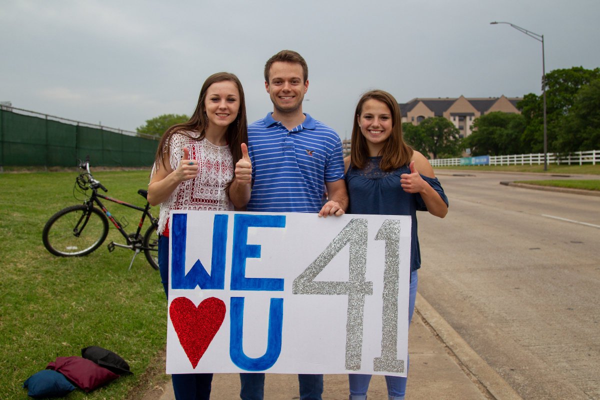 three Aggies standing with a sign reading "We love you 41"