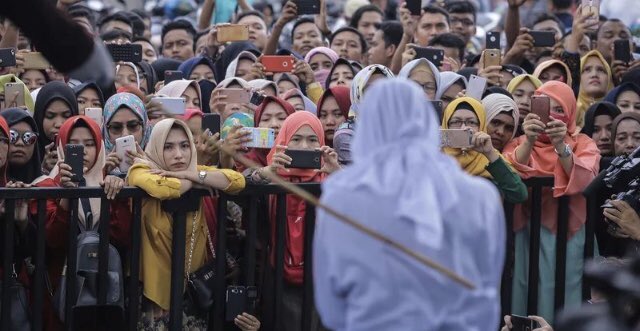 Perempuan ini dihukum cambuk di Aceh. Perempuan2 lain datang menonton dan memotret. Solidaritas antar perempuan?
