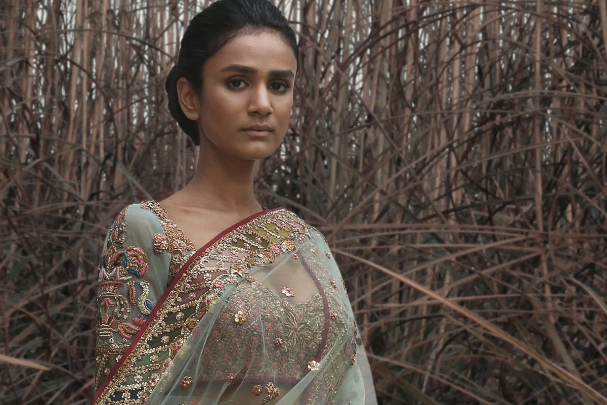 A pale tourmaline green tulle lehenga encrusted with handsewn Kachi-patti gotta embroidery.  The lehenga is paired with a delicate choli and a sheer odhna.