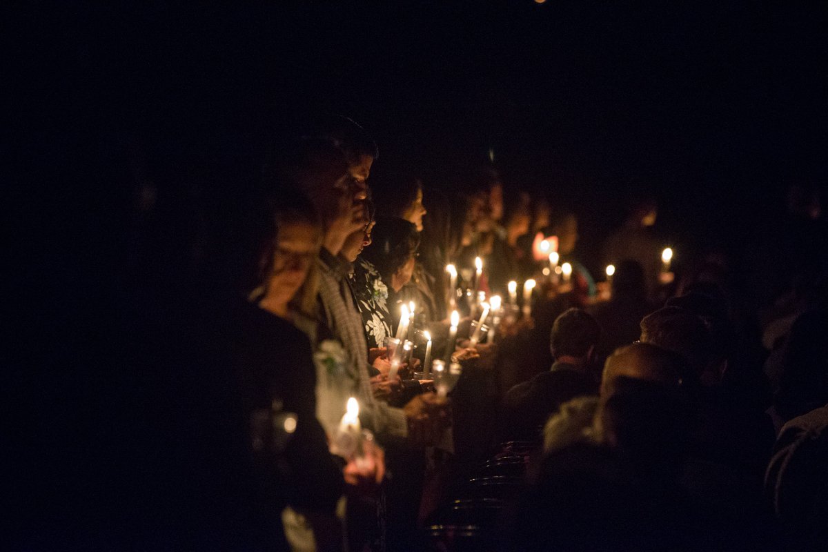 a line of people holding candles in darkness
