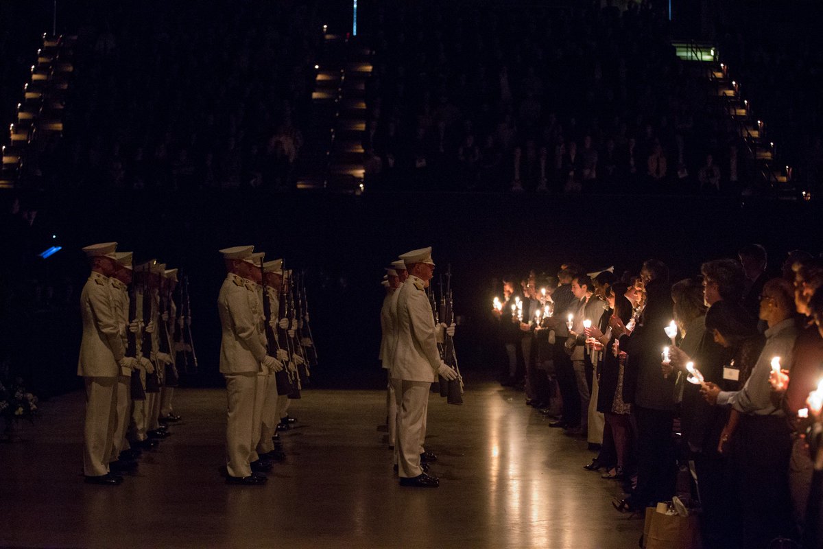 Ross Volunteers wearing white uniforms and holding guns for a 21 gun salute standing in front of people holding candles