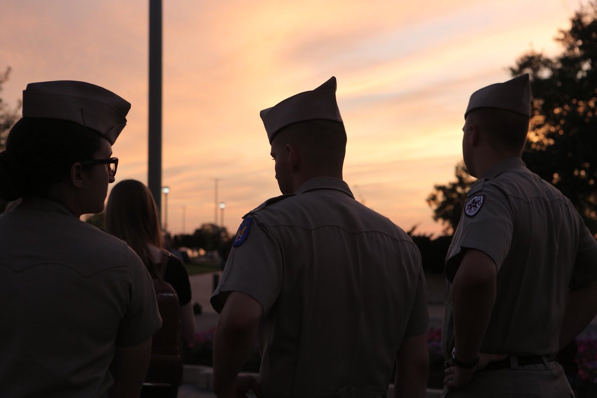 Shot from behind three cadets with the sun setting in the backgrouns