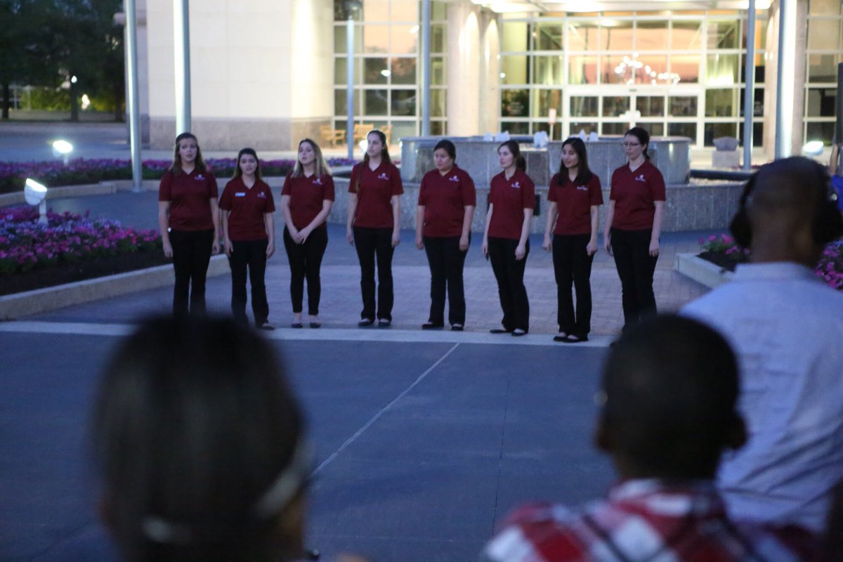 Eight Aggies leading a song in front of the library