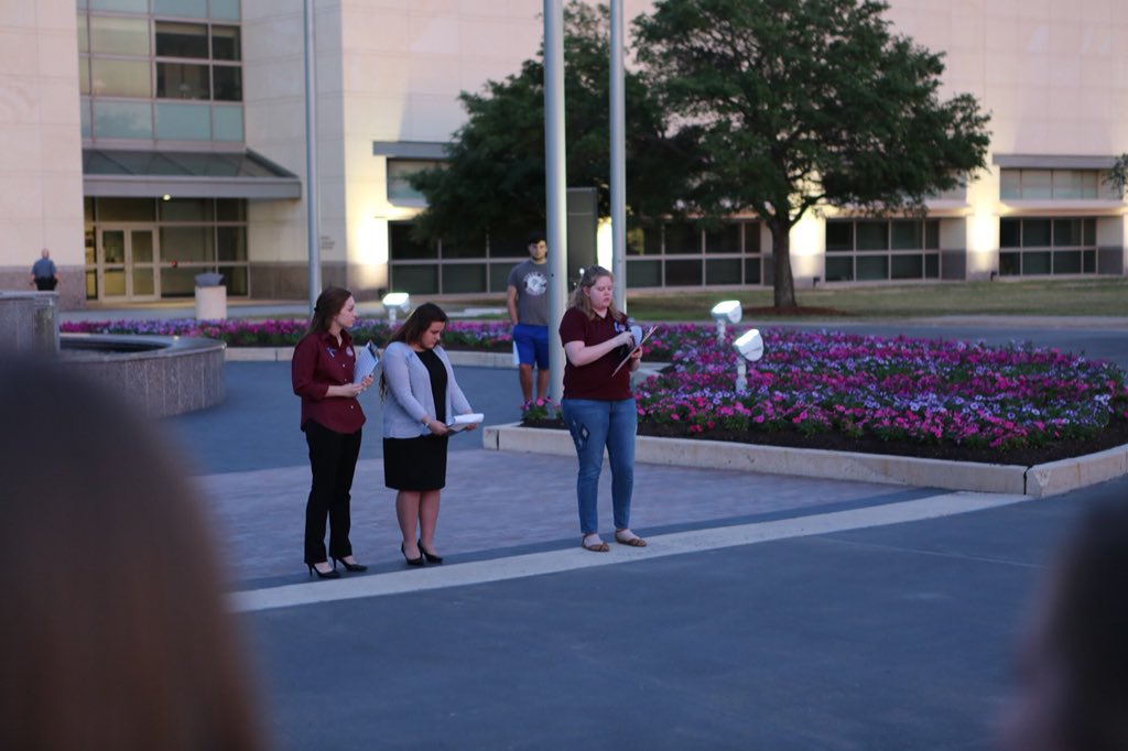 Three students talking to crowd with microphones