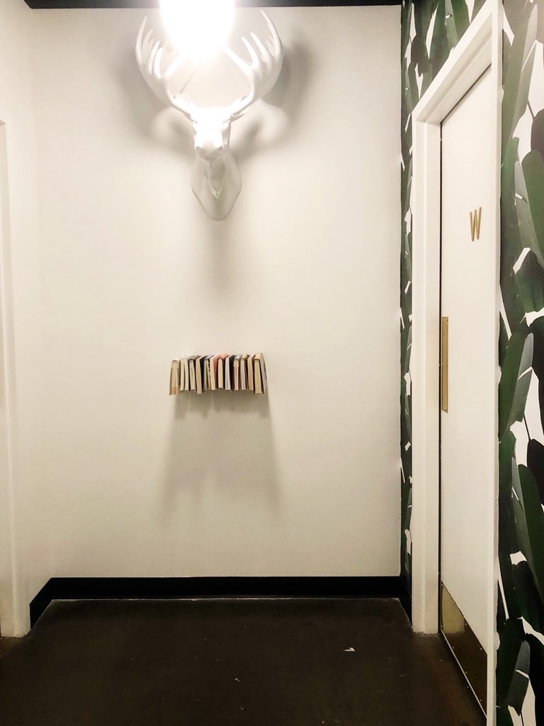 cameronstrang's tweet photo. I’m dead. 😂 This week I hung a bookshelf in front of our office bathrooms as a joke. You know, reading material. Then I told @calvincearley he should curate the selection for us ... and I just saw what he did. This might be one of the subtly funniest things I’ve ever seen. 😂😂 https://t.co/S7eOKbNYUf