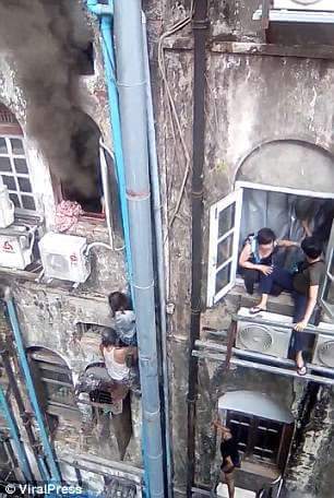 Ref;'Spider-Man' climbs up downpipe of burning building to rescue woman stranded on a window ledge as trapped residents threaten to jump