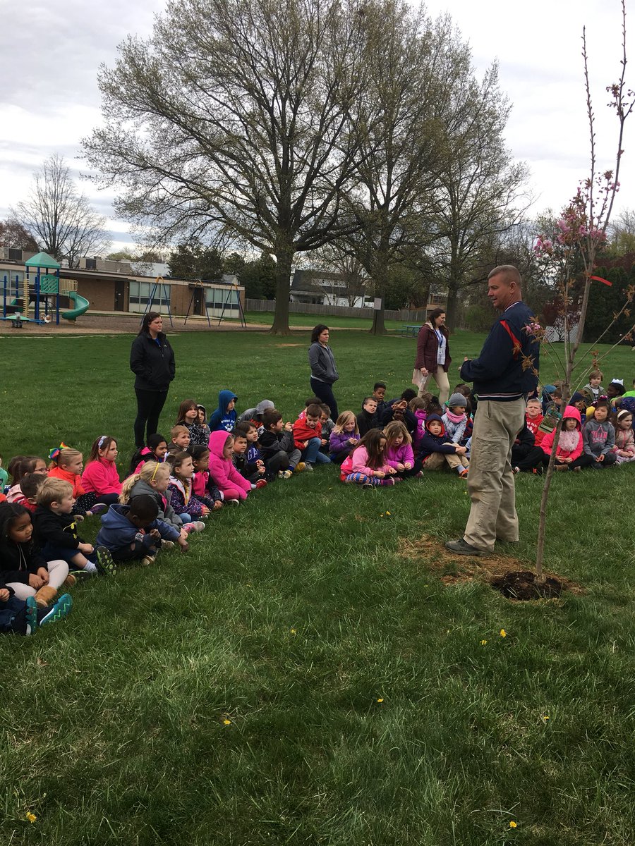 Kindergarteners celebrate Arbor Day planting and watering a tree.