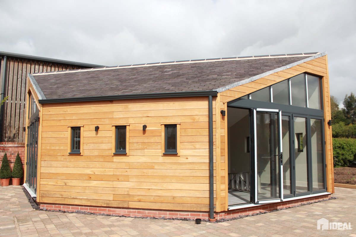 IdealBJS's tweet photo. A separate hexagonal building clad in oak with aluminium anthracite grey bi-fold doors, windows a brick fire pit inside, designed for hosting parties. #teamideal https://t.co/xSA24ScUeo