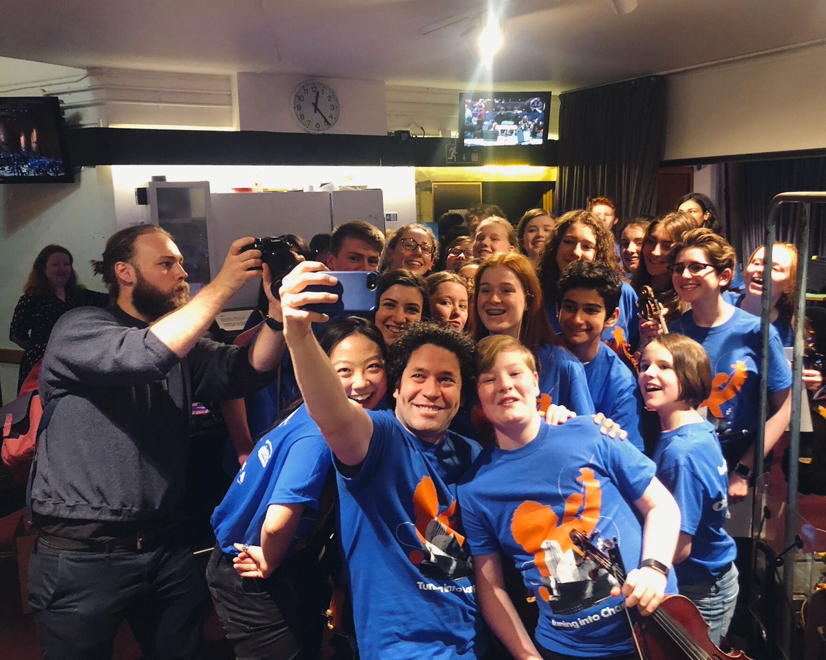 LAPhil's tweet photo. A heartwarming scene from todayโs Tuning into Change student leadership symposium at the @BarbicanCentre. Earlier this morning, @GustavoDudamel led students from the UK and from our very own #YOLA program in a special open rehearsal. Can you imagine? โค๏ธ #LAPhilTour https://t.co/H9K4VWgTj3