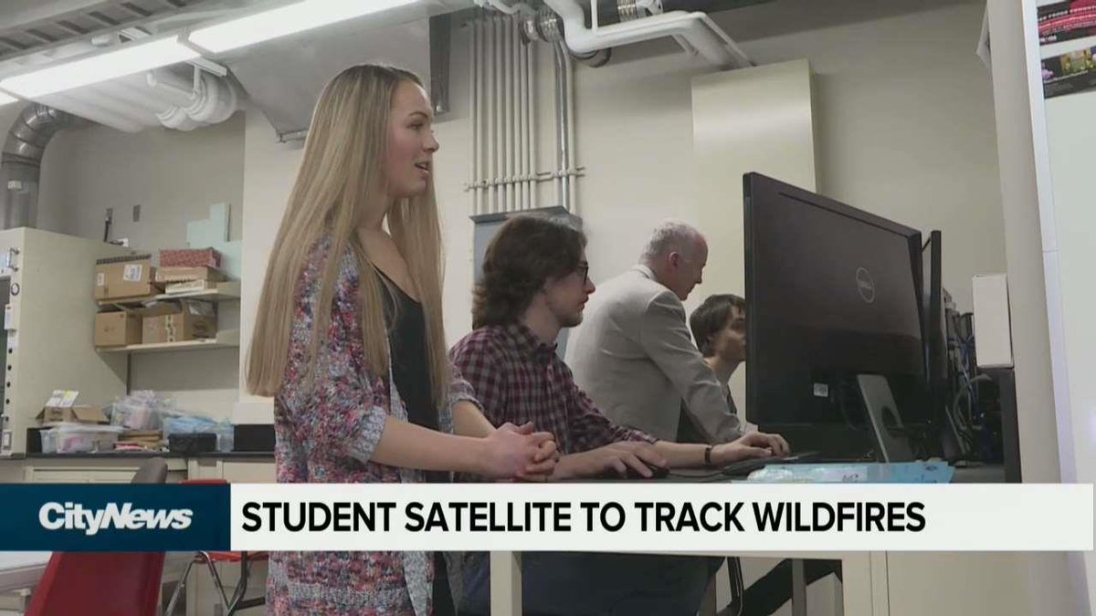 A group of students working on a computer which controls a satellite