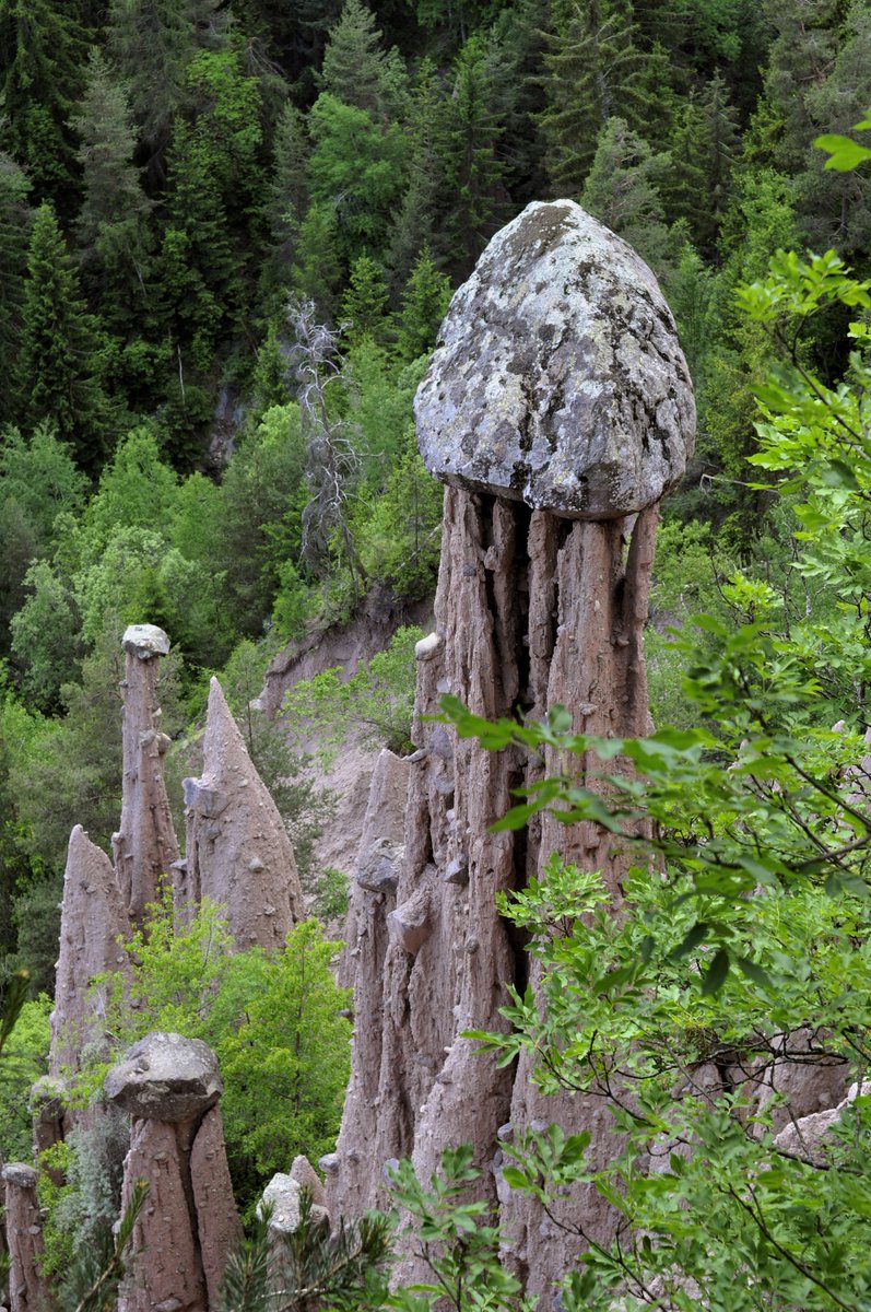 qikipedia's tweet photo. The Piramidi di terra are an eerie natural phenomenon that can be found in northern Italy. The soft clay immediately below a boulder is protected from weather erosion, creating natural, spindly towers with a rock on top. (Image: Gregorini Demetrio) https://t.co/Y97eARKzit
