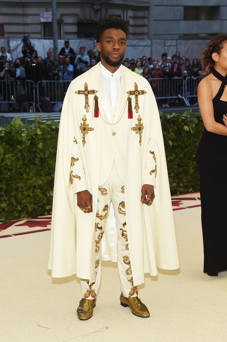 voguemagazine's tweet photo. Black Panther star @chadwickboseman is in one of the night’s more avant-garde looks: an ivory cape with gold beaded crosses and a matching embellished suit.

See more from our #MetGala live blog: https://t.co/QI2DYOSQZO https://t.co/dX3ozEG0wT