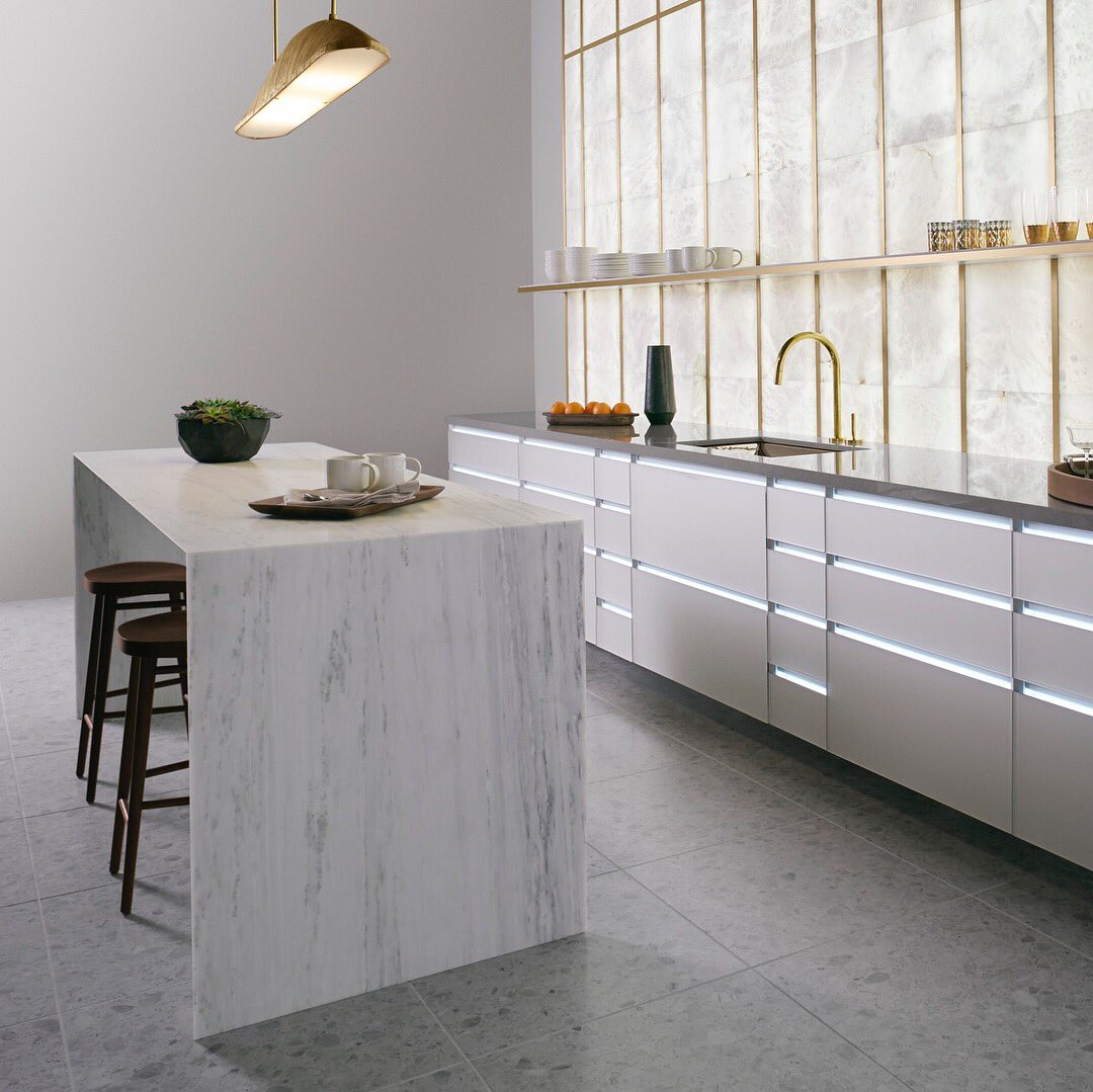 This modern kitchen brings the outdoors in by featuring earthy elements like natural stone and unlacquered brass pieces.