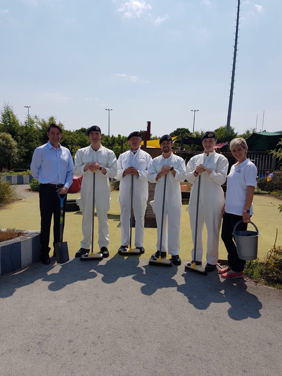 2 members of the Rainbow Charity next to 4 officers wearing white overalls and holding brooms