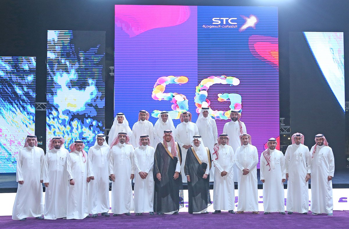 Saudi dignitaries pose for a photo under a 5G banner