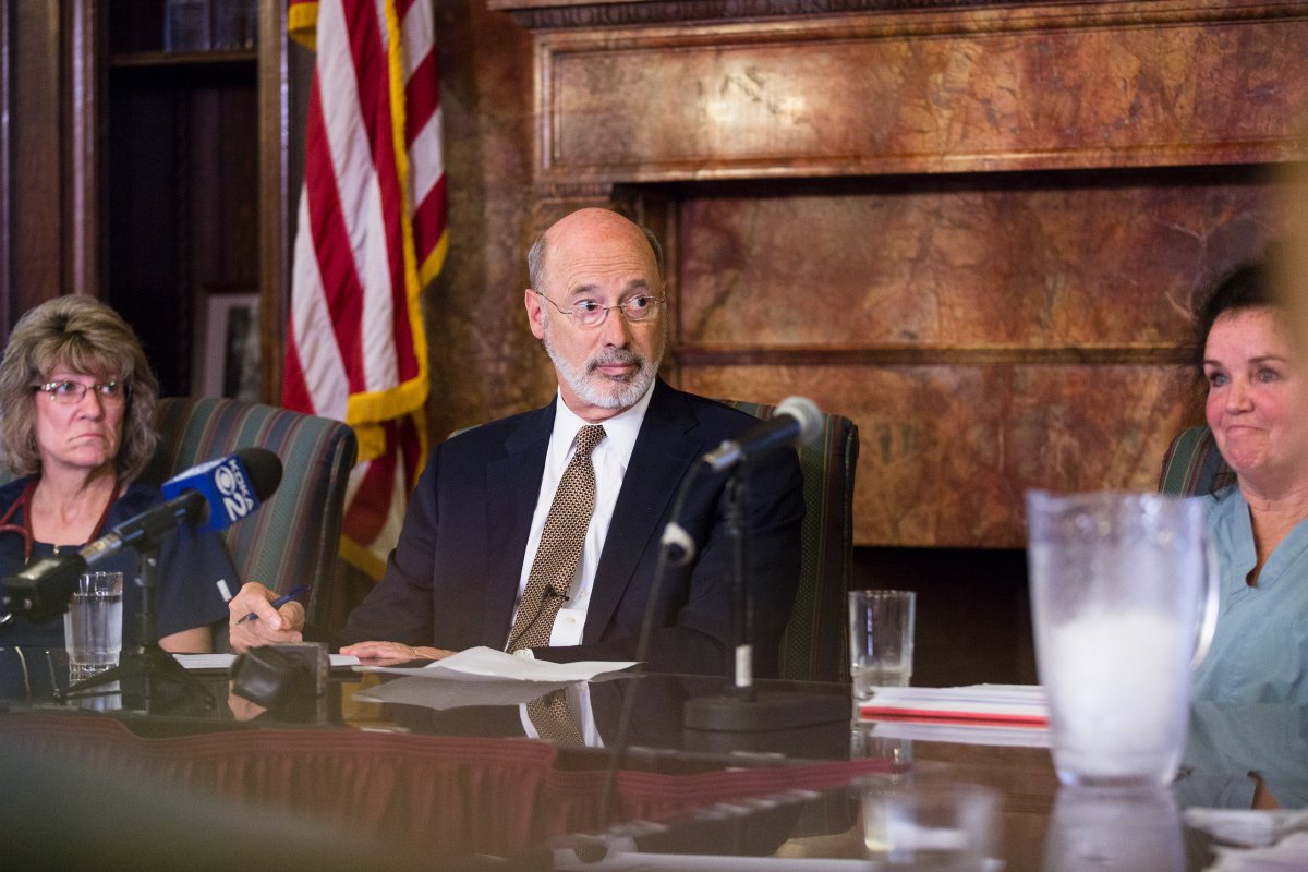 Image of Governor Tom Wolf listening attentively and taking notes as some is speaking.