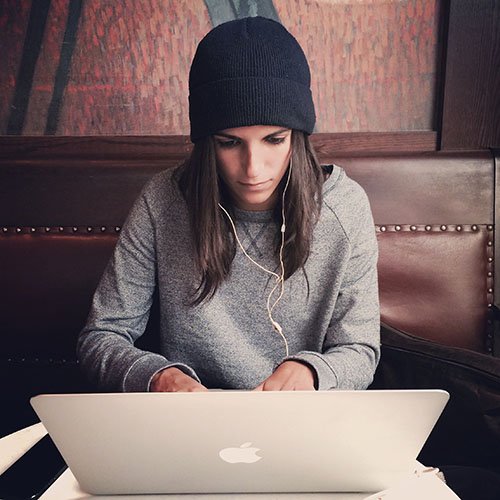 girl wearing a beanie looking at her macbook