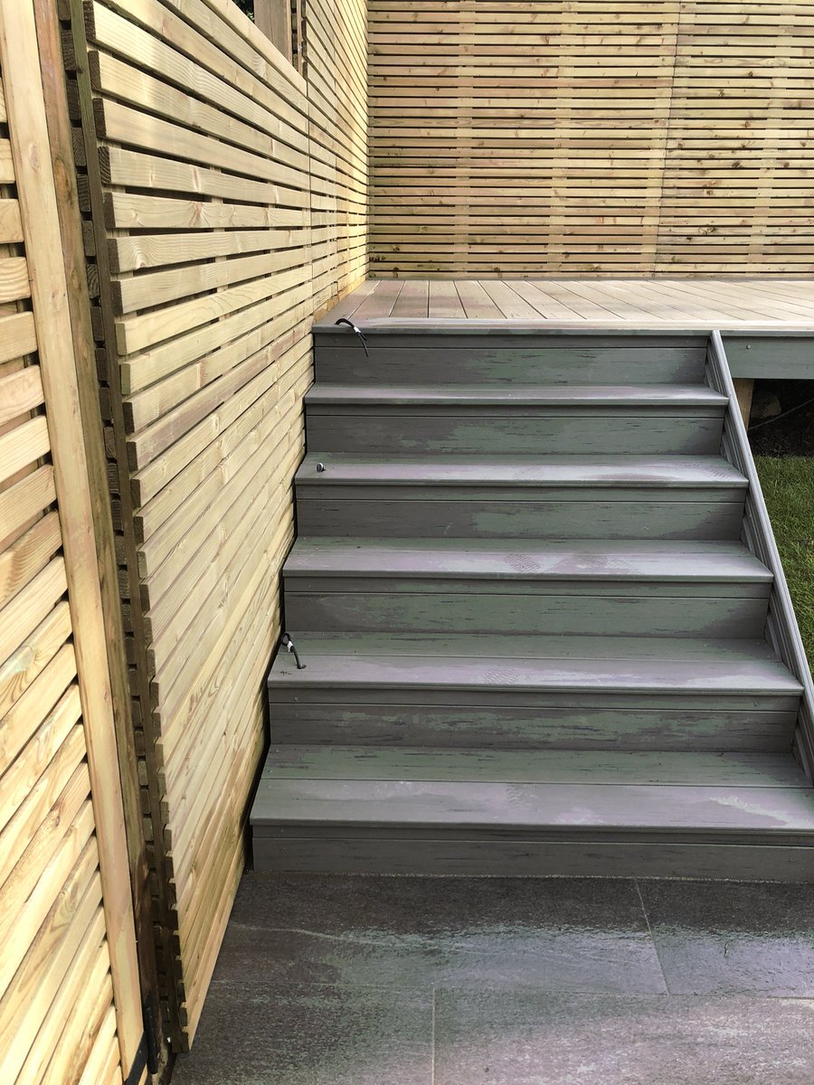 Composite decking with detail around tree, slatted fencing.