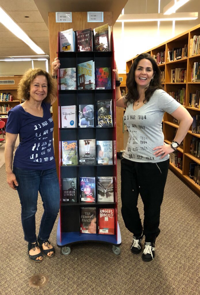 PortLibrary's tweet photo. Kerry Spillane and I modeling library check out shirts(thank you Kerry)surrounded by library books!  Check out cards are missed! https://t.co/nuLW61DPTS