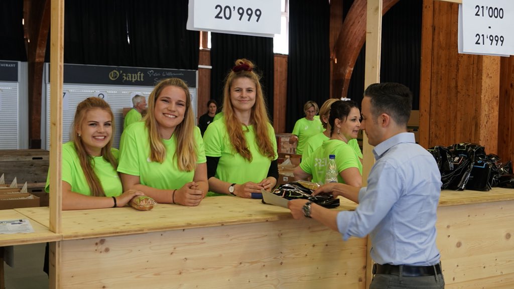 gpbern's tweet photo. Freudige Gesichter auf beiden Seiten der Startnummerausgabe: Insgesamt stehen über 1000 Helferinnen und Helfer am GP-Wochenende im Einsatz. #gpbern #volunteers #freiwilligenarbeit https://t.co/aAsPKKNGMV