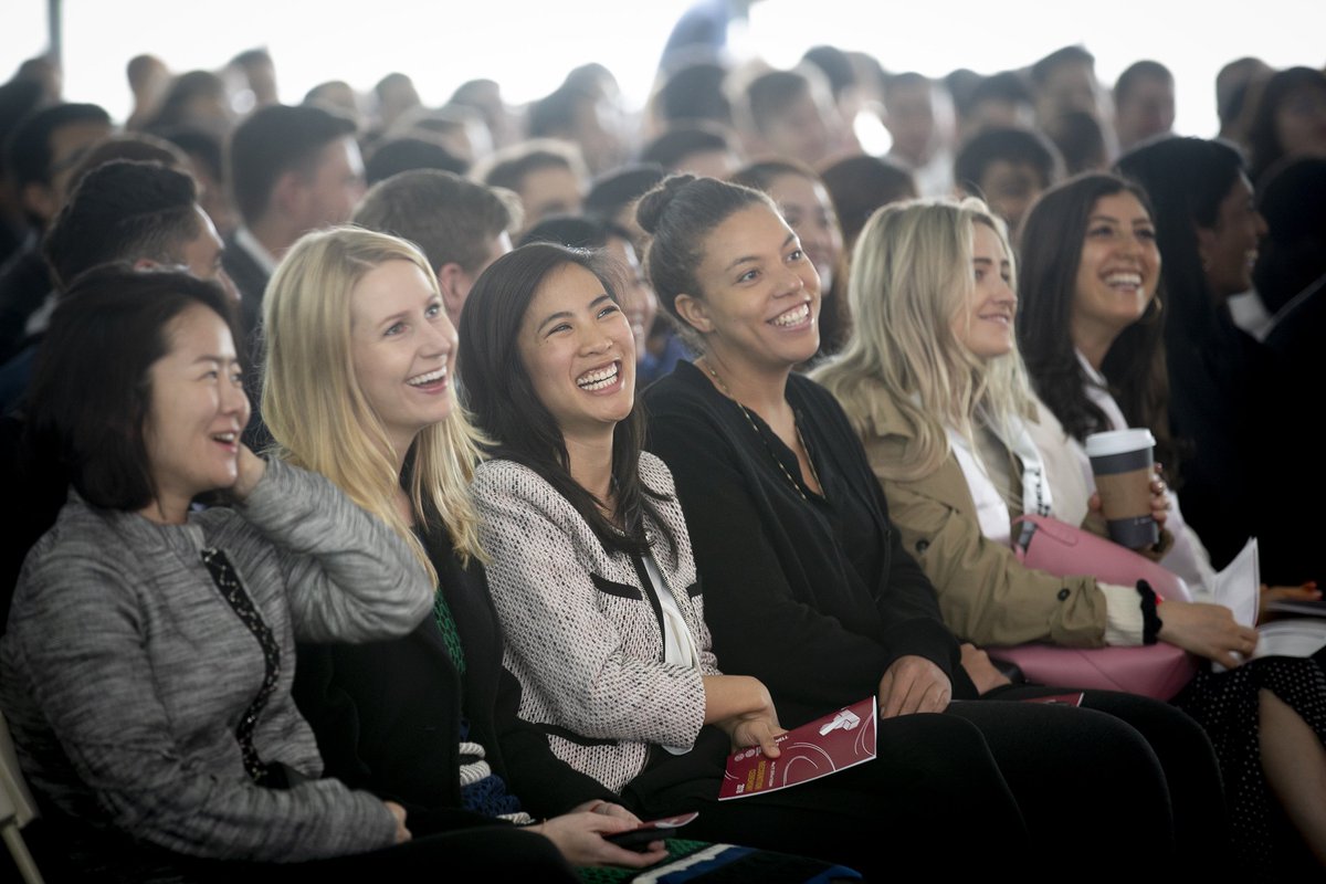 6 women graduates smiling and laughing in the audience.