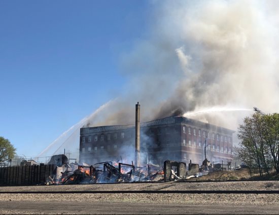 Manitowan's tweet photo. Downtown #brandon on fire in what is described as the worst fire in this cities history. Ash falling in backyards kil away. #bdnmb #cbcmb. Fire crews cont to battle blaze which has spread to several business's, and 1 res complex. Pics compl of #ebrandon https://t.co/pwnBBfhzgZ