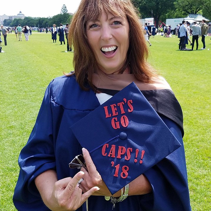 Graduate holding decorated cap with "Let's Go Caps!! '18"