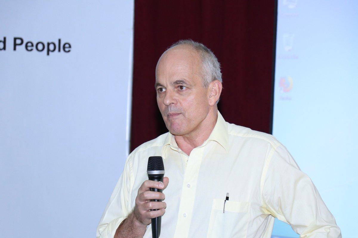 Mr Gavin McGillivray, Head of the DFID Office in India is seen wearing a pink shirt and holding a mike.