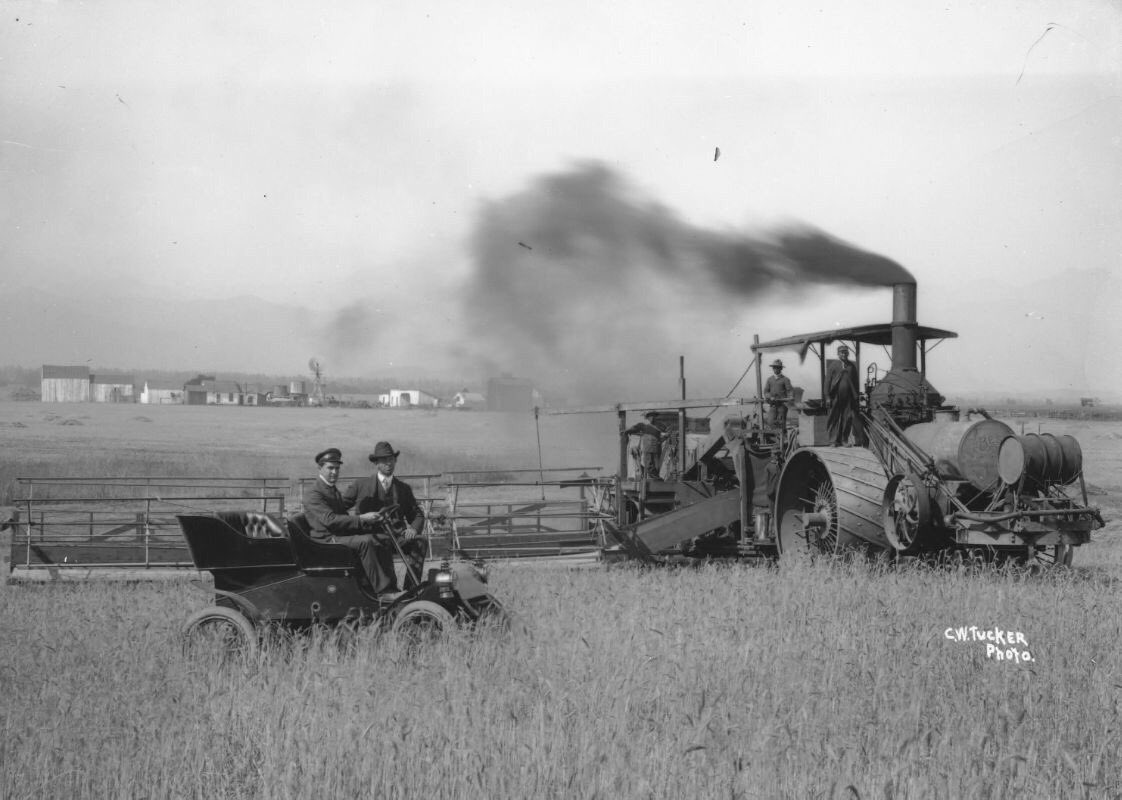 Some serious harvesting going on here with this steam  threshing machine. The car is a model A Ford. Presumably chauffeur driven and the farmer posing.