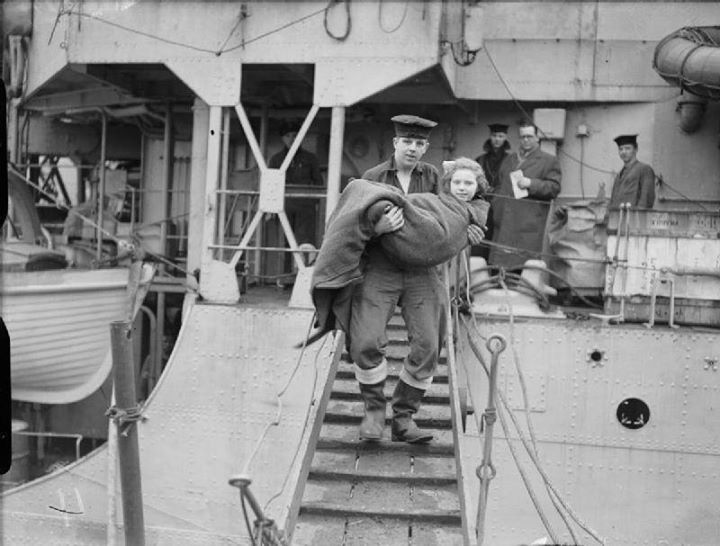 A seaman carries a young injured Norwegian girl ashore from HMS Onslaught after docking at Gourock, Scotland, 27 February 1945. The girl had suffered two broken arms.
