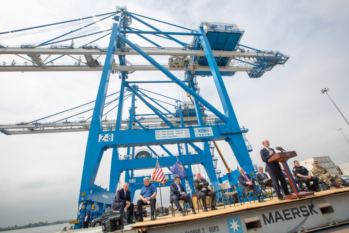 Image of Governor Tom Wolf providing remarks at the foot of a two super post-Panamax cranes.