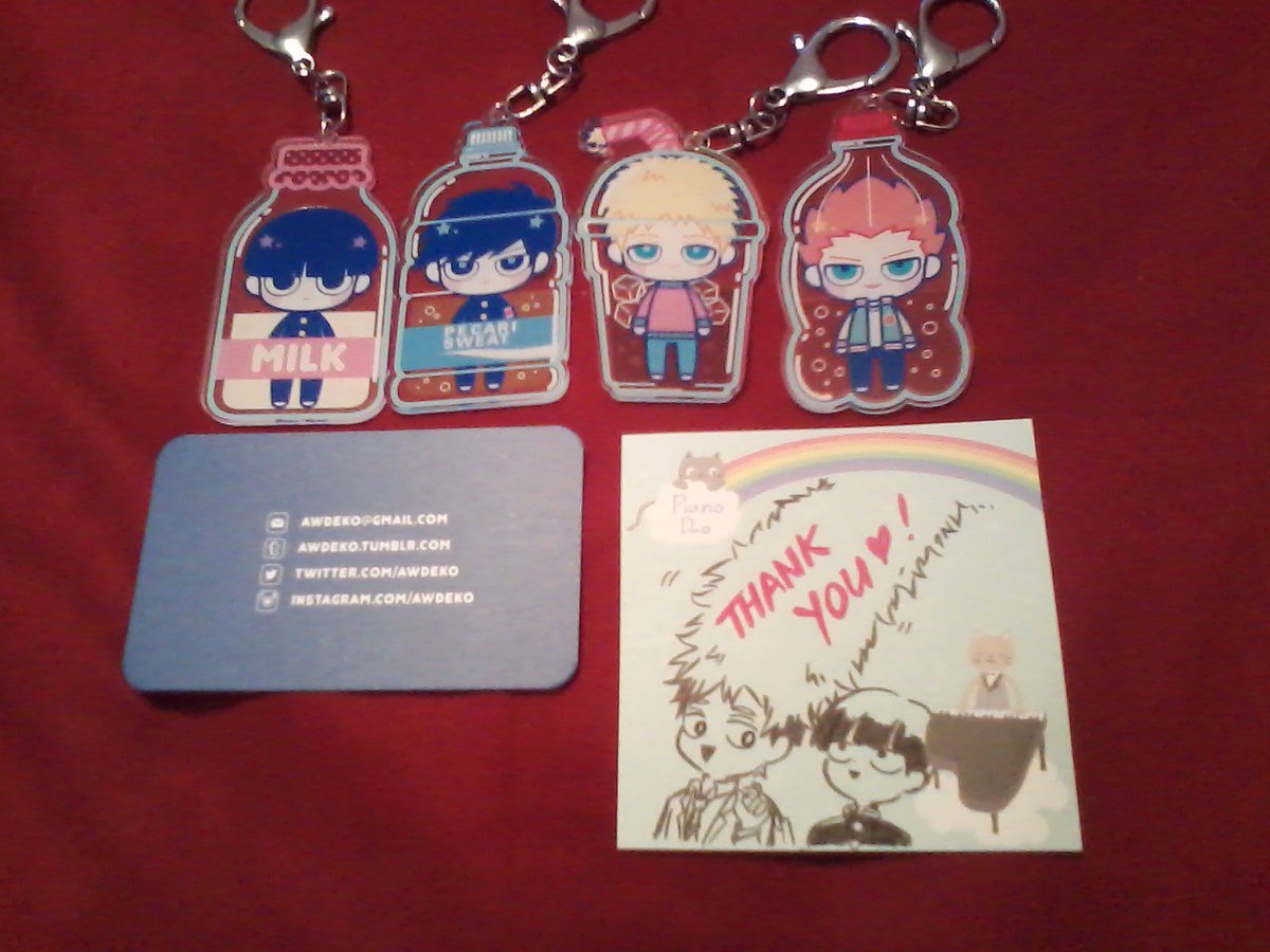 Awdeko's clear acrylic Mob Psycho 100 charms, featuring Mob, Ritsu, Teru, and Shou. Also Awdeko's business card and note of thanks with a Mob and Teru doodle.