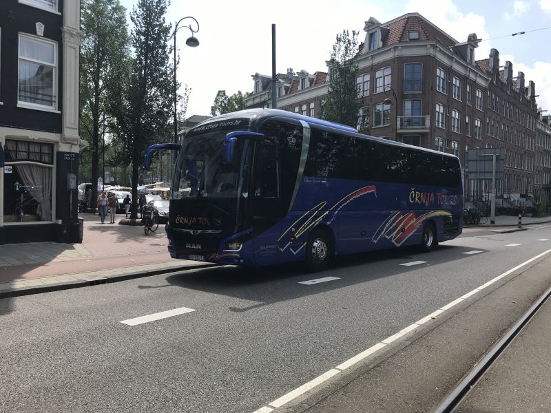 Toeristenbus midden op de weg geparkeerd op Mauritskade bij Dappermarkt. Buschauffeur en passagiers nergens te bekennen.