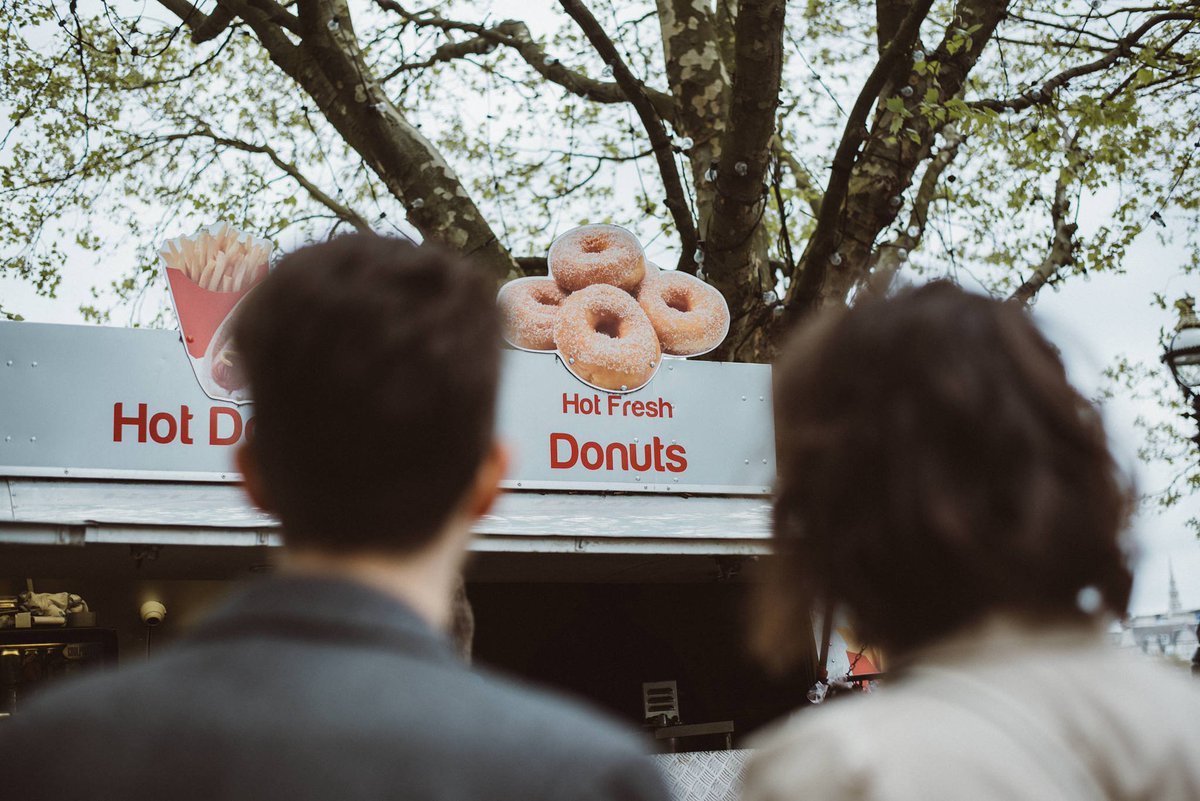 Photo of a couple looking at a doughnut stand.
